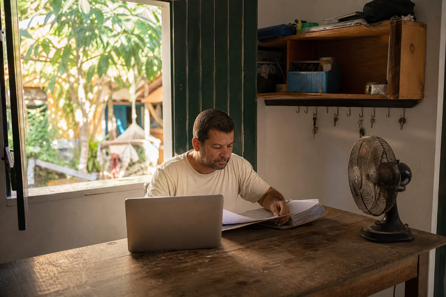 Dono de pousada trabalha no notebook em escritório improvisado nos fundos da casa